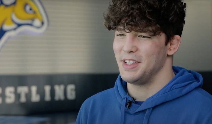 Male student answering interview questions in a wrestling space.