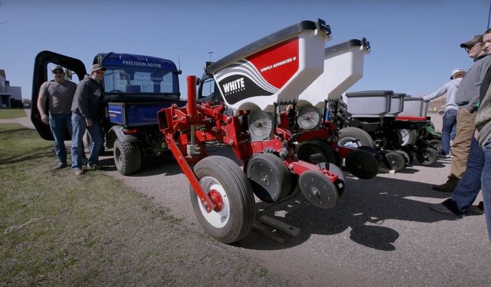 Group of students observing autonomous agriculture equipment outside.